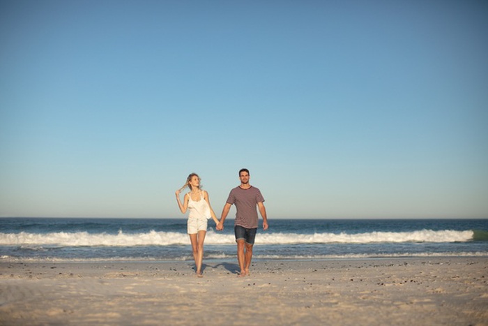 Wealthy couple walking by the Mississippi Gulf Coast at sunset