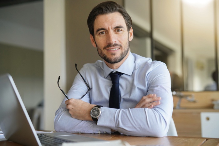 homme d'affaires intelligent et &eacute;l&eacute;gant au bureau avec ordinateur portable et appareil photo