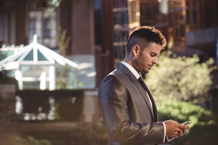 Well-dressed professional man checking MillionaireMatch on phone.