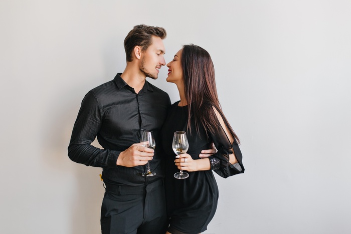 Married couple kissing at party holding champagne glasses