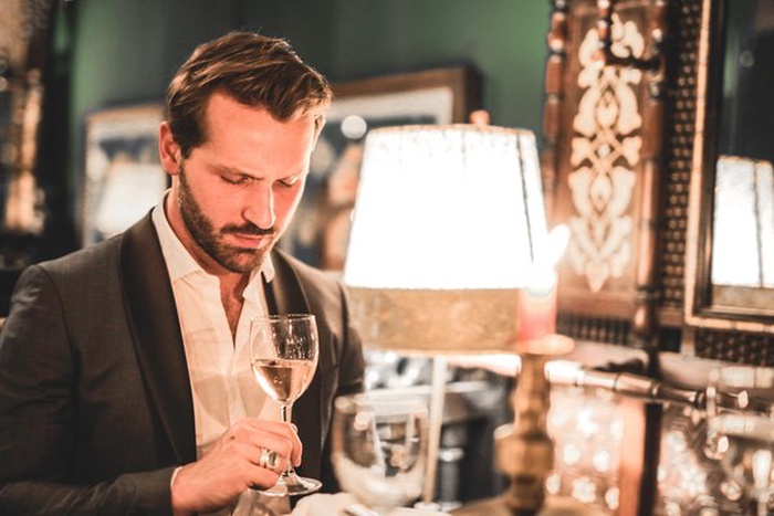 Well-dressed gentleman drinking at a Montclair wine bar in warm evening light.