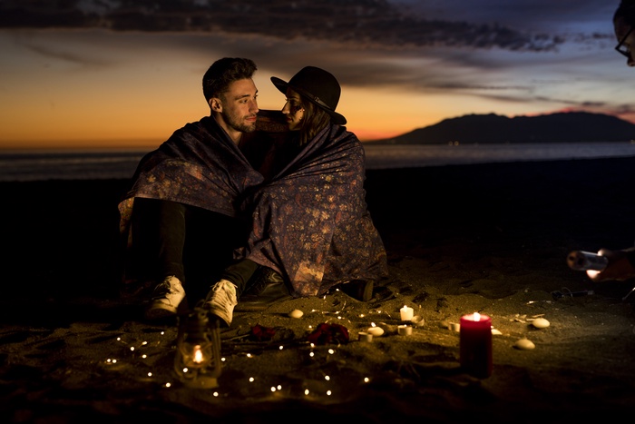 couple on the blanket siting on the sea shore