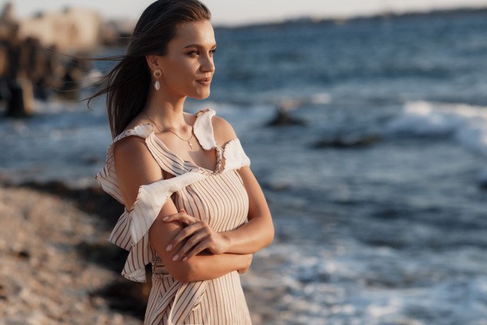 A young and beautiful woman is gazing into the distance by the sea.
