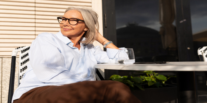 Senior woman sitting at a café table smiles