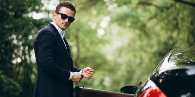 Homem rico elegante ao lado de carro de luxo