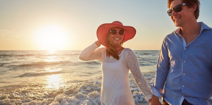 Wealthy couple walking by the beach at sunset