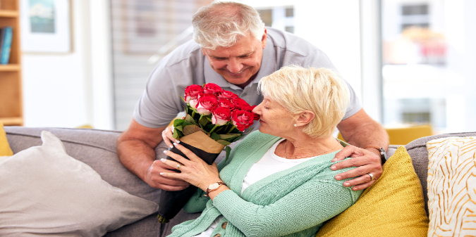 An elderly couple holding flowers on a date