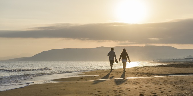 couple walking on the beach at dusk