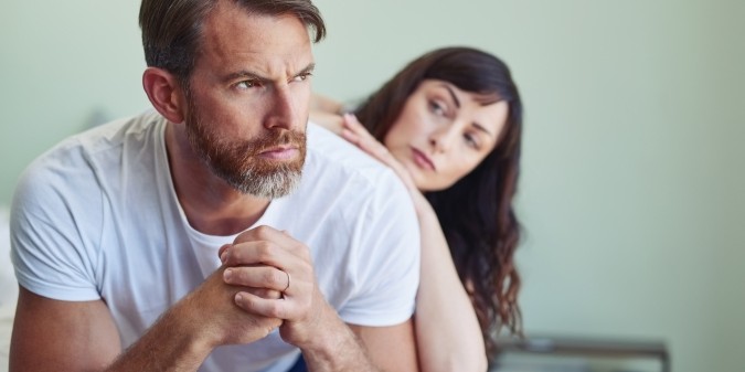 Couple in emotional distance on bedroom floor
