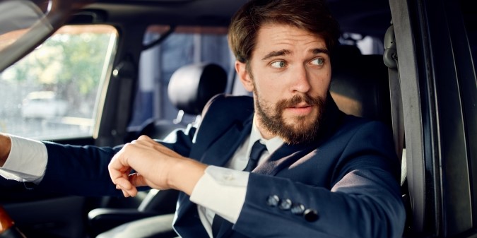 Man in suit sitting confidently inside luxury car