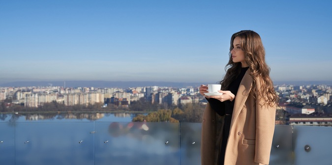 woman standing on balcony with cup of coffee