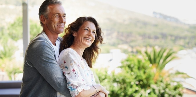 Pareja madura feliz abrazada en patio de casa